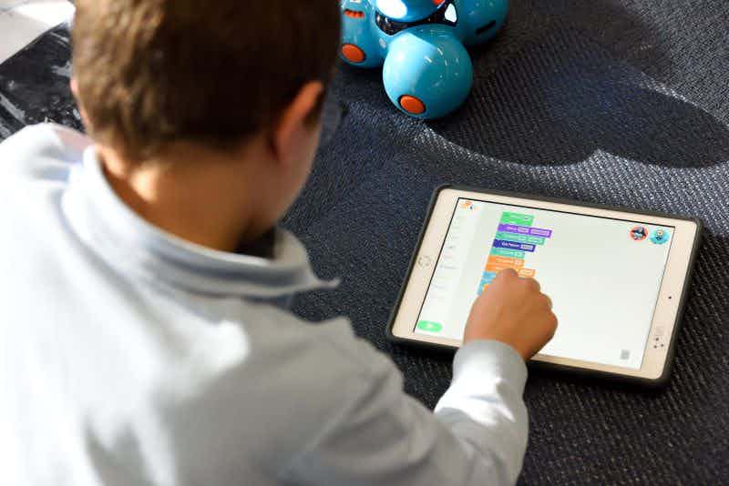 child in a classroom playing a learning game on a tablet
